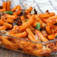 Piatto fumante di pasta alla siciliana in teglia, con melanzane, pomodoro e formaggio filante.