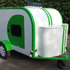 Caravane blanche et verte au design unique, rappelant une goutte d'eau. Parfaite pour des escapades écologiques.