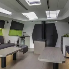 Interni moderni di una nave, con divani, tavoli, cucina e oblò sul soffitto.