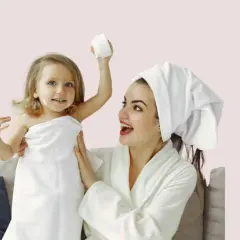 Mère et fille profitent d'un moment de **soin du visage pour petite fille fait maison**. La petite est enroulée dans une serviette, avec de la crème sur le nez.