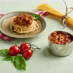 Pyszny sos do spaghetti przepis na talerzu, obok pomidorki i makaron.