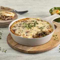 Pyszna zapiekanka z mięsem mielonym, polana ciągnącym się serem, podana z sałatką.
