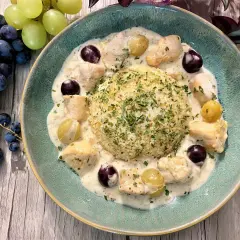 Un délicieux poulet au raisin crémeux, servi avec du riz et garni de persil frais. Des grappes de raisins noirs et verts complètent cette assiette appétissante.