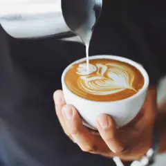 Un barista crea un disegno a cuore con latte per cappuccino su un caffè.