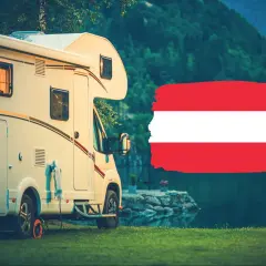 Kamper zaparkowany nad jeziorem w Karyntii, Austria. Obok flaga Austrii.