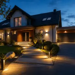 Nowoczesny dom z oświetleniem ip44 na zewnątrz. Podświetlana ścieżka prowadzi do drzwi, a lampy podkreślają architekturę i ogród.