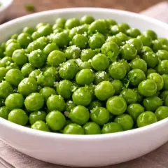 Un bol de petits pois frais, brillants et assaisonnés de sel et de persil, prêts pour la cuisson.