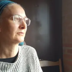 Anna Nachman, med glasögon och en turkos scarf, blickar utåt.