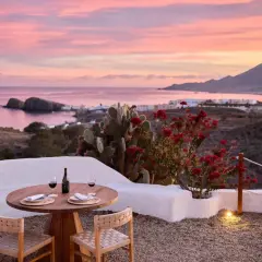 Mesa lista para cenar en el restaurante La Loma Almería, con vistas al mar y un atardecer rosado.