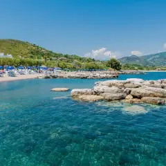 Spiaggia attrezzata con ombrelloni e lettini, mare cristallino e rocce affioranti. Un angolo di paradiso nel Cilento, mare da sogno.