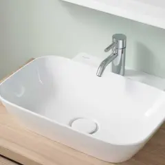 Lavabo blanc moderne sur meuble en bois, robinetterie chromée. La hauteur du lave-main wc est idéale pour un usage confortable.