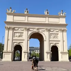 Brama Brandenburska w Poczdamie, gdzie leży to piękne miasto, z ludźmi i psami na placu.