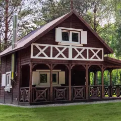 Urokliwy projekt dom kanadyjski z werandą i białymi okiennicami, otoczony zielenią.