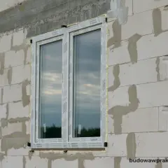 Okna w ścianie z bloczków betonowych, z widocznym pianką montażową. To maksymalny otwór bez nadproża, gotowy na dalsze prace budowlane.