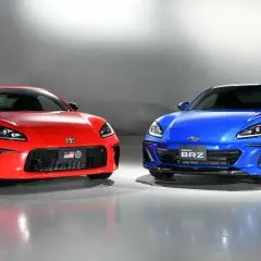 Dwa sportowe coupe, czerwona Toyota GR86 i niebieski Subaru BRZ, stoją obok siebie, gotowe do wyścigu.