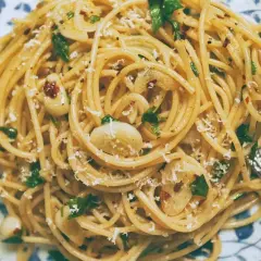 Pyszne spaghetti aglio e olio z czosnkiem, natką pietruszki i płatkami chili, posypane parmezanem.