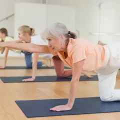 Des seniors en pleine forme sur un tapis, pratiquant un exercice de **parcours équilibre senior**.