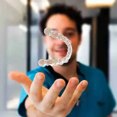 Un dentista sonriente muestra un alineador invisible, explicando cómo funcionan los alineadores invisibles para corregir la sonrisa.
