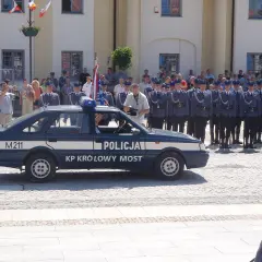 U pana Boga w ogródku obsada: policjanci w mundurach stoją w szeregu obok radiowozu.
