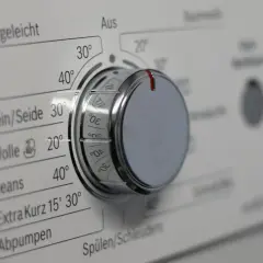 Drehknopf einer Waschmaschine mit verschiedenen Waschprogrammen wie Pflegeleicht, Fein/Seide, Wolle und Jeans.