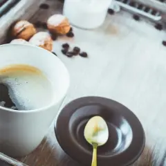 Eine Tasse schwarzer Kaffee gesund, mit Keksen und Kaffeebohnen auf einem Holzteller.
