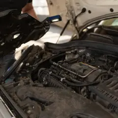 Mechanik z latarką bada silnik, przygotowując się do tego, jak odkamienić układ chłodzenia w samochodzie.