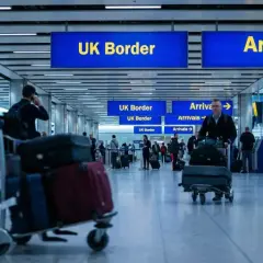 Ludzie z bagażami przechodzą przez lotnisko w Wielkiej Brytanii, kierując się do UK Border i Przylotów.