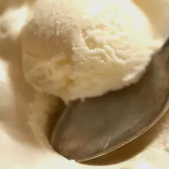 Kremowe lody z serka wiejskiego, idealne na deser. Łyżeczka zanurzona w słodkiej masie.