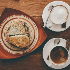 Ein Sandwich und ein Café Americano auf einem Holztisch.