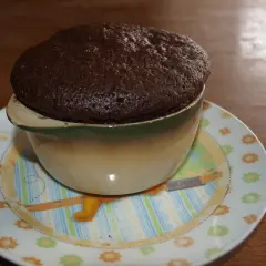 Puszyste, gorące ciasto czekoladowe w kubku, prosto z mikrofali, na talerzyku z zabawnym wzorem.