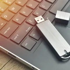 Silberner USB-Stick liegt auf einer Laptop-Tastatur. Vielleicht hilft das, den USB-Stick RAW zu reparieren.