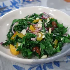 Ensalada siciliana vibrante con col rizada, gajos de naranja, cebolla morada, aceitunas y almendras laminadas.
