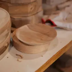 Assiette en bois brut sur un tour, avec des copeaux. Une belle idée de tournage sur bois pour créer des objets uniques.