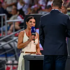 Kobieta z mikrofonem Canal+ na tle trybun stadionu.