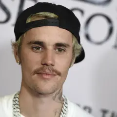 Justin Bieber w czapce z daszkiem i z wąsami, wygląda jakby świętował swoje urodziny.