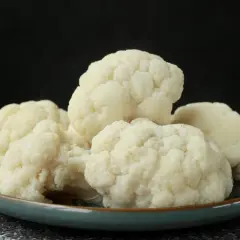 Montón de coliflor cocida en un plato verde, lista para tu receta.