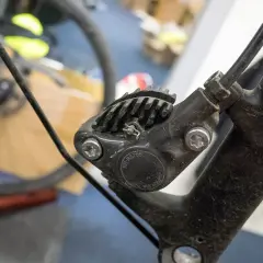 Close-up of a bicycle's hydraulic disc brake caliper, showing the brake fluid top and cooling fins.