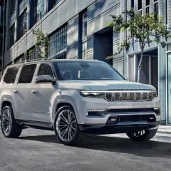 Elegancki, biały Wagoneer parkuje na miejskiej ulicy, obok nowoczesnych budynków.