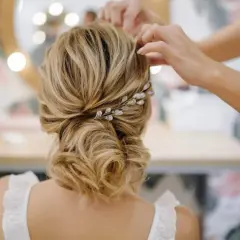 Une mariée se fait coiffer des cheveux lâchés, ornés d'une barrette scintillante. Une coiffure mariage cheveux lâchés élégante.