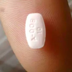 Biała tabletka z oznaczeniem "A-009 10" na palcu. Może to być lek, np. Abilify, pomagający w leczeniu schizofrenii.