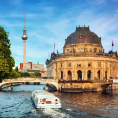 En båt på Spree-floden passerar Bode-museet och Fernsehturm, en av Berlins måsten.