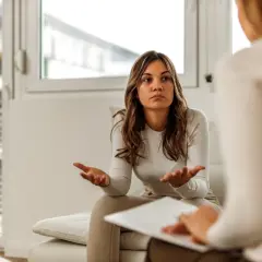 Kobieta rozmawia z psychologiem, gestykulując rękami.