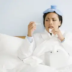 Donna a letto con impacchi freddi in testa, termometro e fazzoletti, preoccupata per la sua salute, quasi un'ipocondriaca.