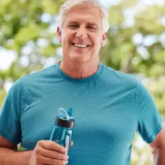 Homme souriant tenant une gourde, prévenu des conséquences de la déshydratation sur le cerveau.