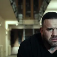 Martyn Ford, acteur aux multiples tatouages, dans un couloir sombre. Une scène qui pourrait figurer dans ses films.