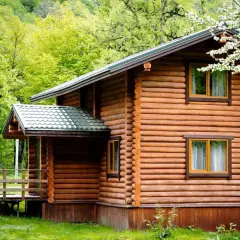 Drewniany domek letniskowy, otoczony zielenią, wygląda jak przytulny budynek mieszkalny.