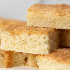 Stapel von saftigen Buttermilch Kokos Kuchenstücken, goldbraun gebacken und mit Kokosraspeln bestreut.