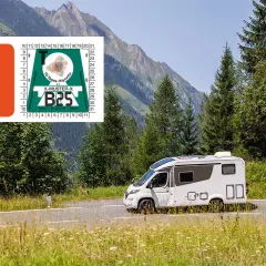 Un camping-car blanc roule sur une route de montagne en Suisse, avec une vignette autoroutière visible.