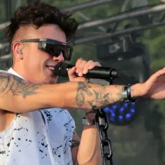 Dawid Kwiatkowski w okularach i z tatuażami śpiewa na koncercie.