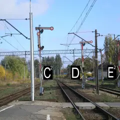 Semafor kolejowy z tarczą i światłami, wskazujący drogę pociągom.